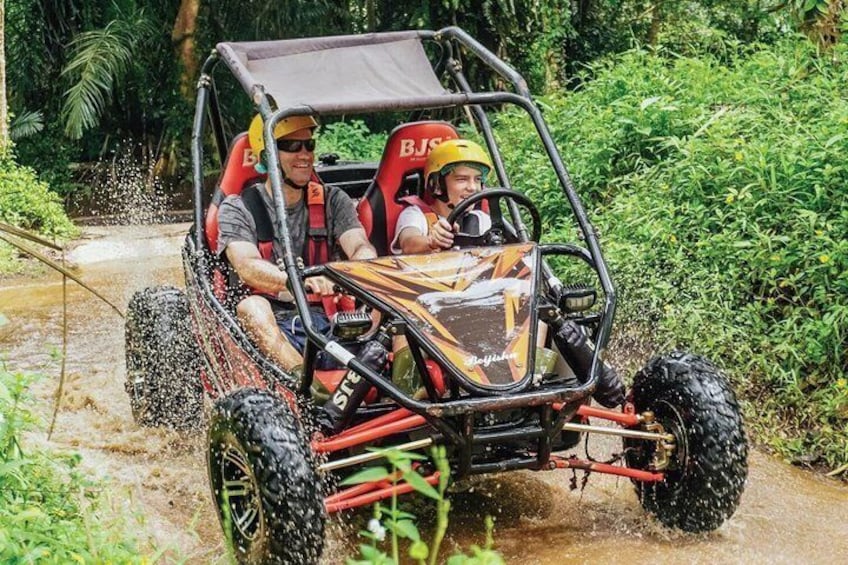 A four-wheeled off-road vehicle on a muddy path surrounded by greenery. 3