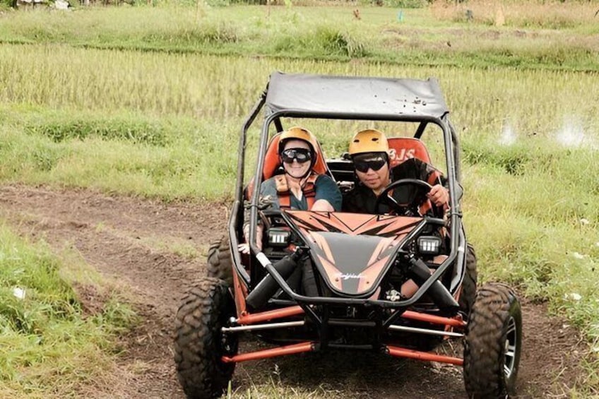 Two people in a dune buggy on a dirt path in a grassy field. 5