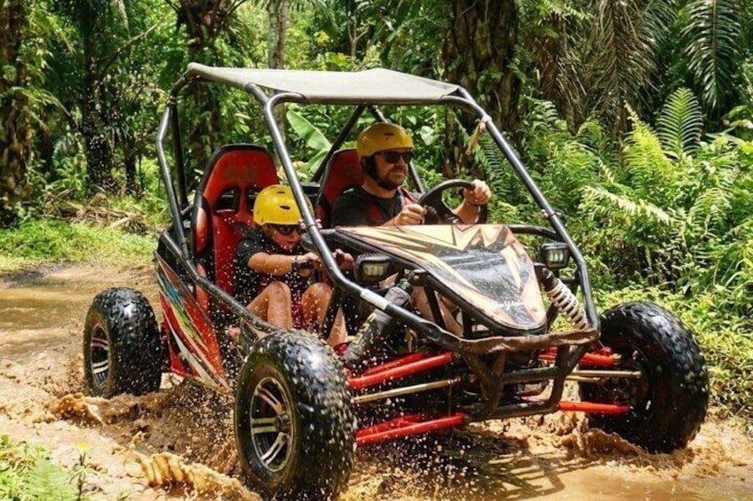 A four-wheeled off-road vehicle with passengers, navigating through a muddy terrain. 1