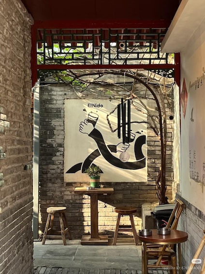 A mural of a hand holding a glass, with a plant on a table, and a red roof above. 1
