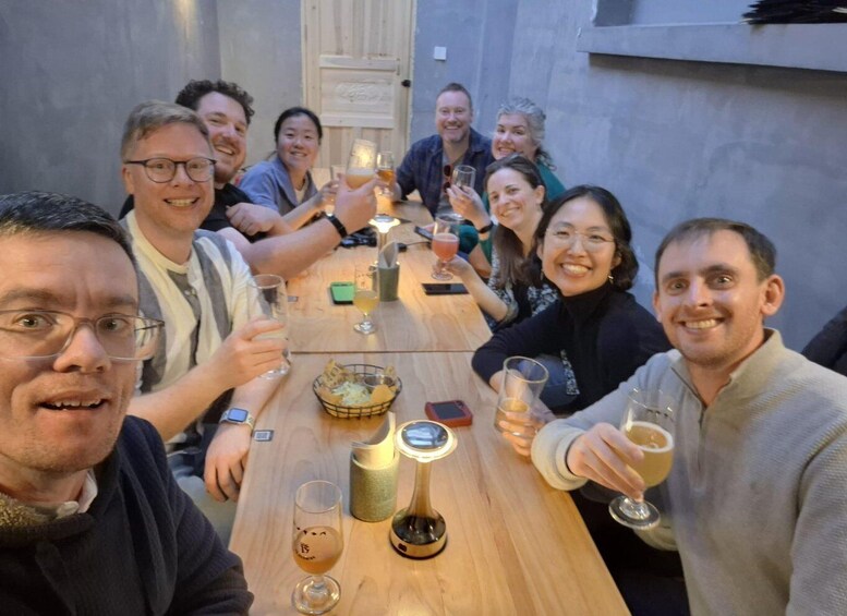 A group of people sitting around a wooden table with drinks, engaged in conversation. 4