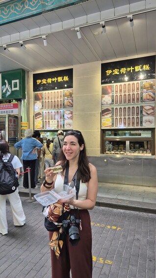 A person holding a food item in front of a food stall with menus in a foreign language. 2