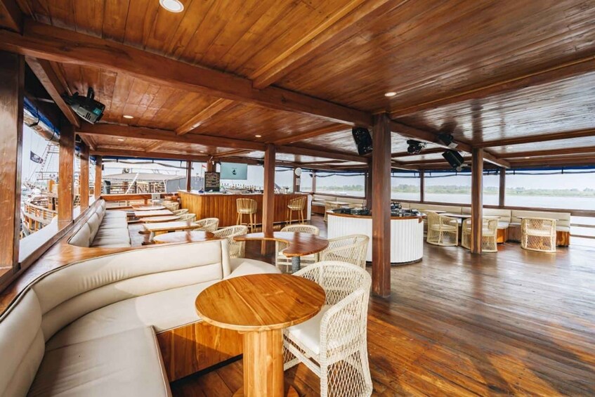 A wooden deck with white wicker furniture, a bar area, and a view of the water. 2