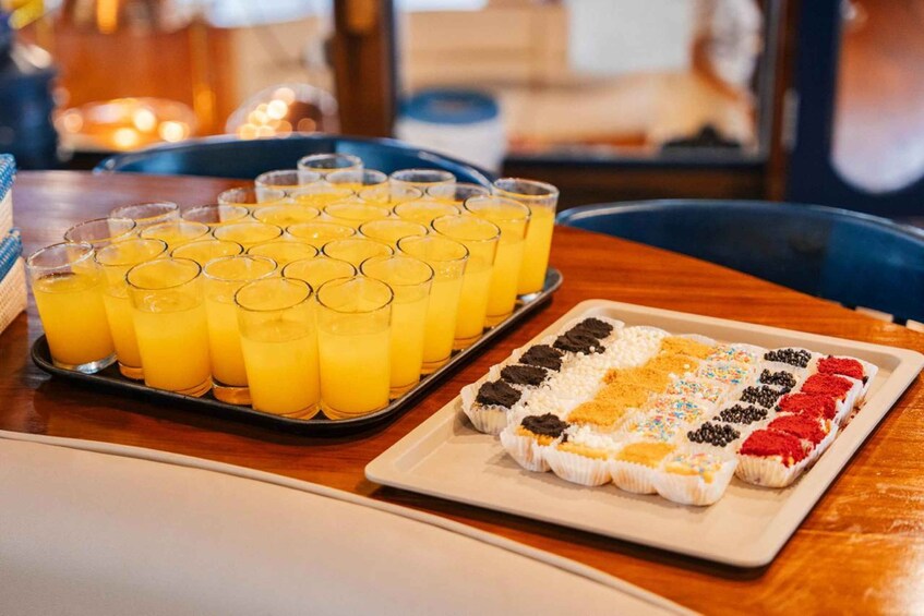 A tray of orange juice glasses and a dessert tray with various toppings. 4