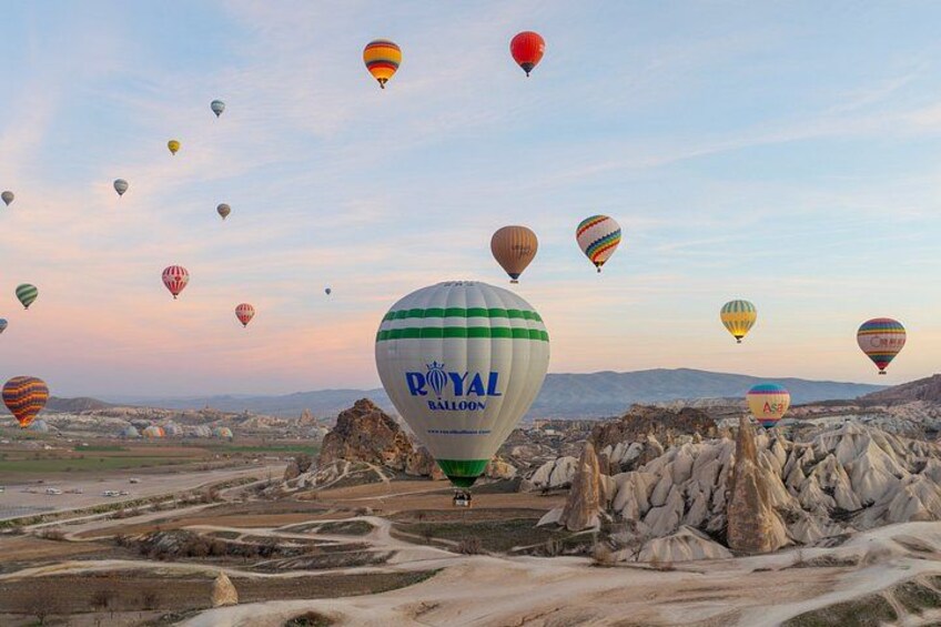 A landscape with multiple hot air balloons, including one with 'ROYAL BALLOON' text, over a rocky terrain with a clear sky. 1