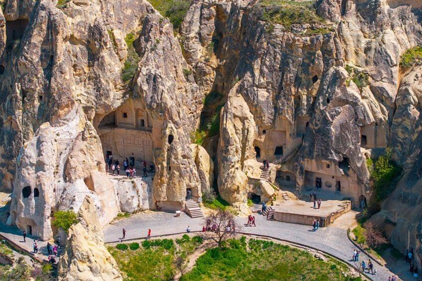 A rock formation with carved structures and a paved walkway. 2