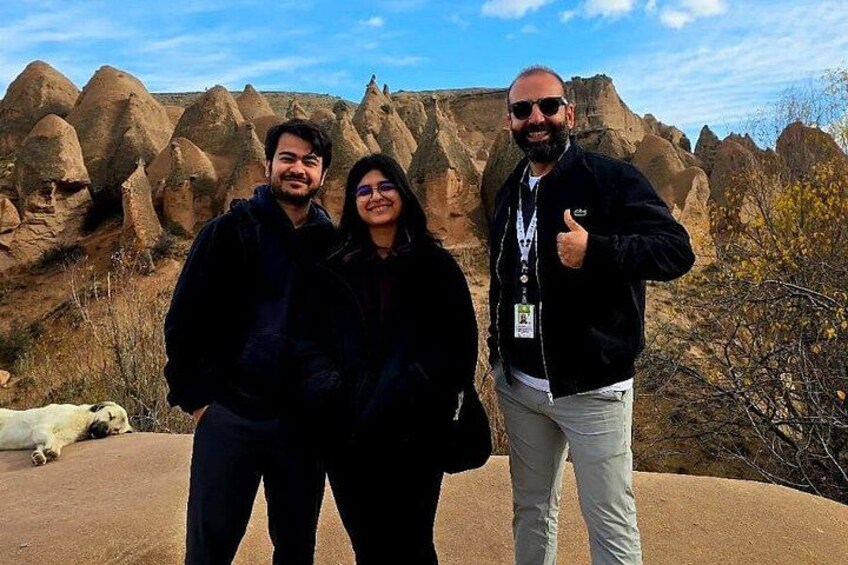 Three people standing in a rocky landscape with distinctive rock formations in the background. 4