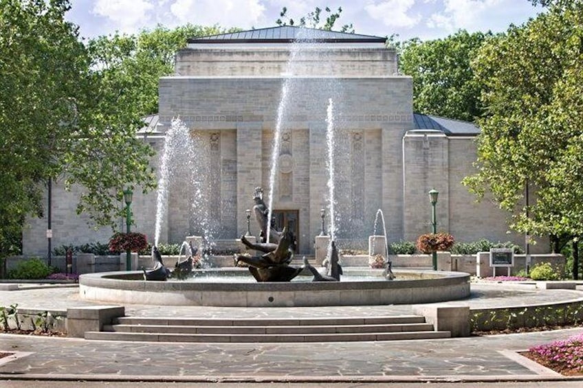 A fountain with water jets in front of a building with columns. 4