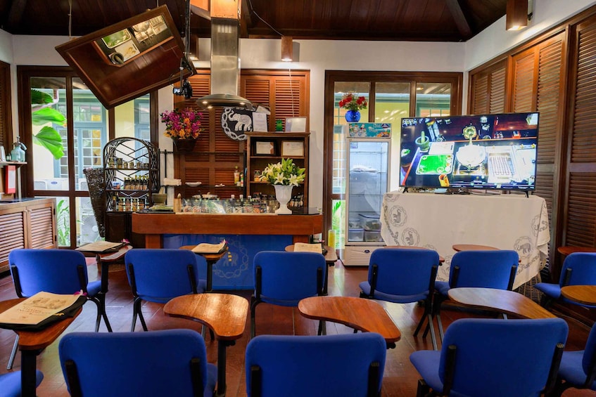 Ein Restaurant mit blauen Stühlen, einer Bar und einem Fernseher, der eine Speisekarte zeigt. 4