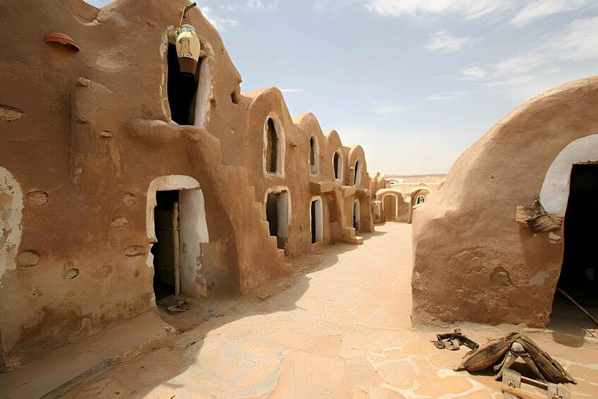 A narrow alley with mud-brick buildings featuring arched doorways and windows. 2