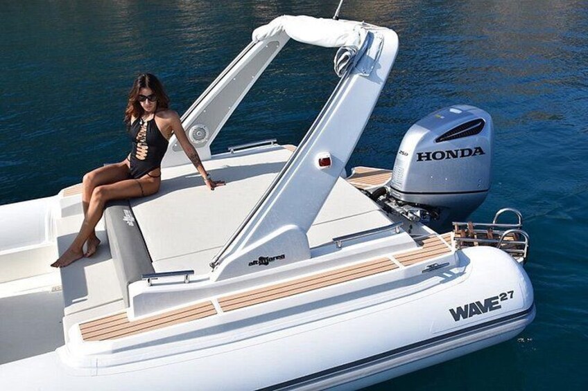 Een witte motorboot met een Honda motor, een vrouw zittend op het dek, en de merknaam 'WAVE27' aan de zijkant. 3