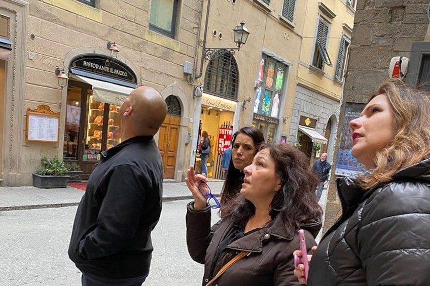 A street scene with a restaurant named 'Ristorante Il Panello' and people standing on the sidewalk. 4