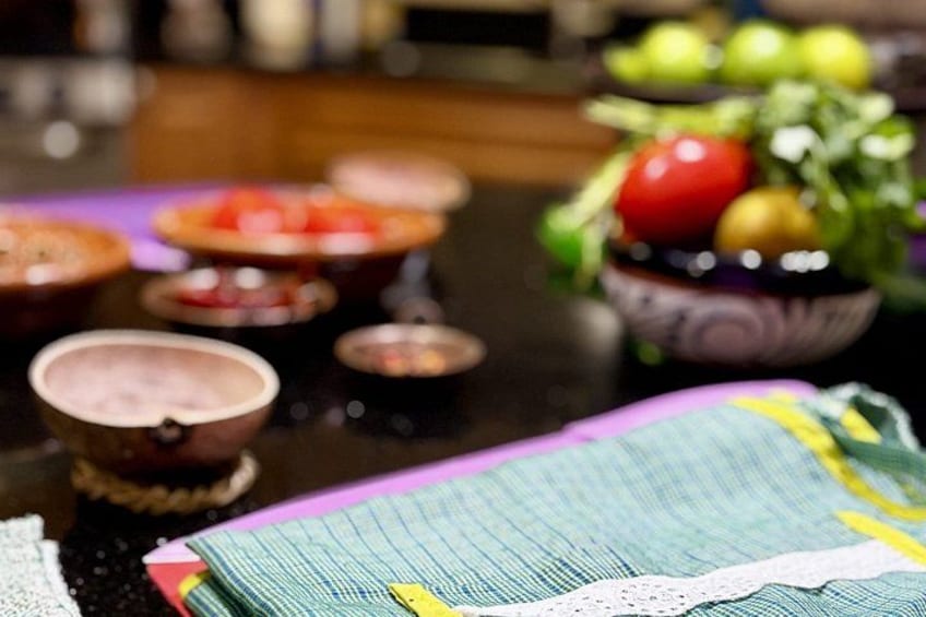 A table with various dishes, a bowl of fruit, and a patterned tablecloth. 2