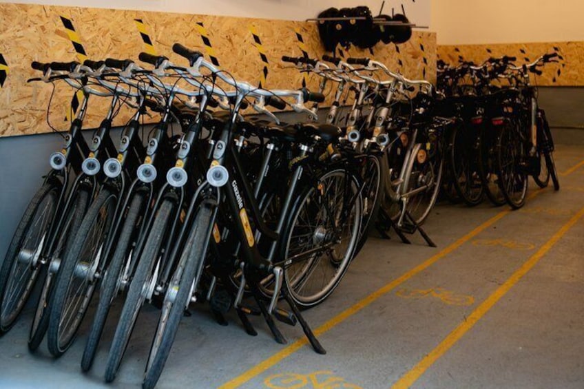 Række cykler parkeret i et garage med gule linjer på gulvet. 2