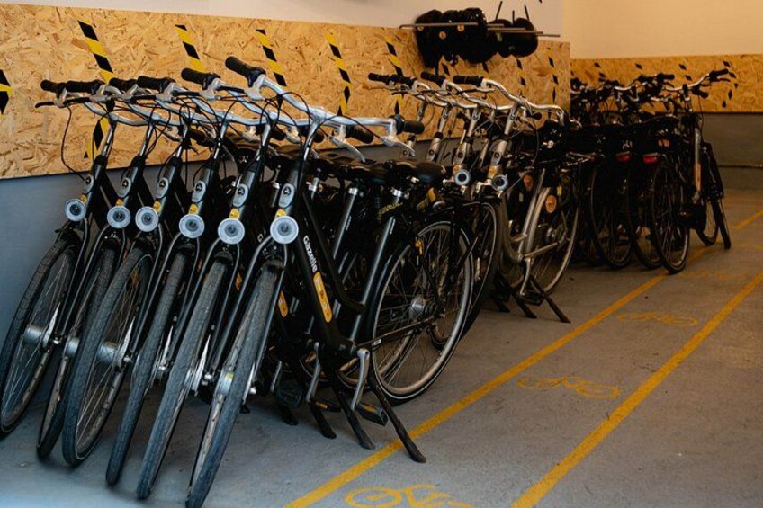 Række cykler parkeret i et garage med gule linjer på gulvet. 2