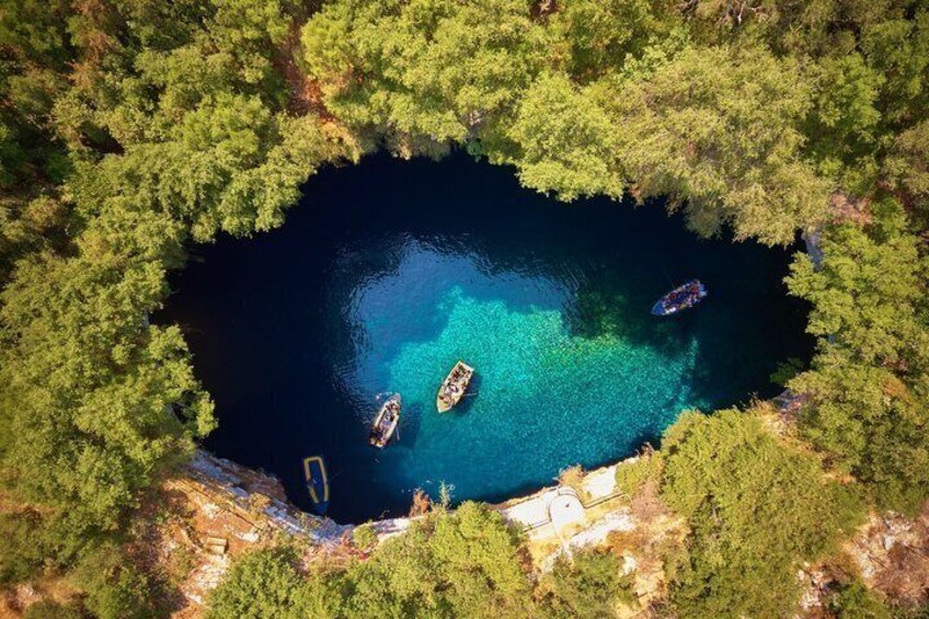 Un lago circular rodeado de un bosque denso, con tres barcos anclados en el agua. 4