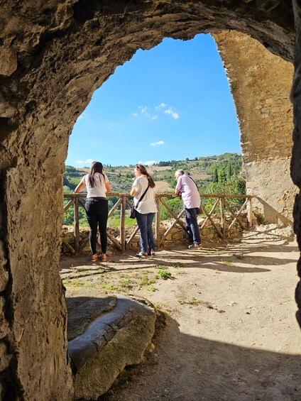 A stone archway overlooking a scenic landscape with a wooden railing. 5