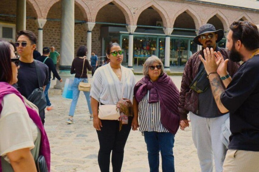 A group of people standing in a courtyard with arches and columns. 4