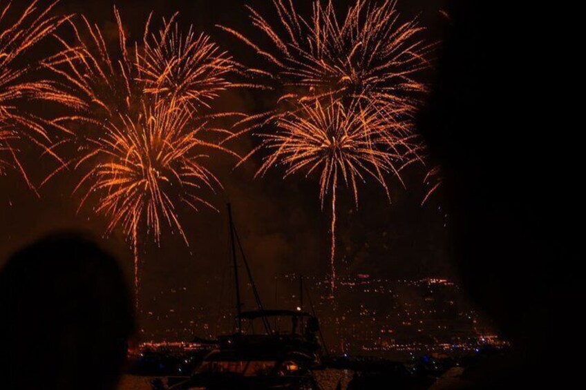 Fireworks over a cityscape with silhouettes of people and a crane. 5