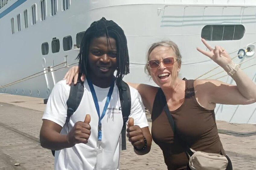 Two people standing in front of a large yacht. 1