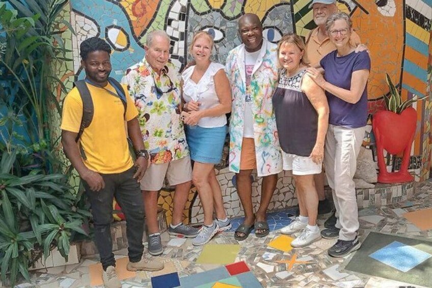 A group of people standing in front of a colorful mosaic wall. 4