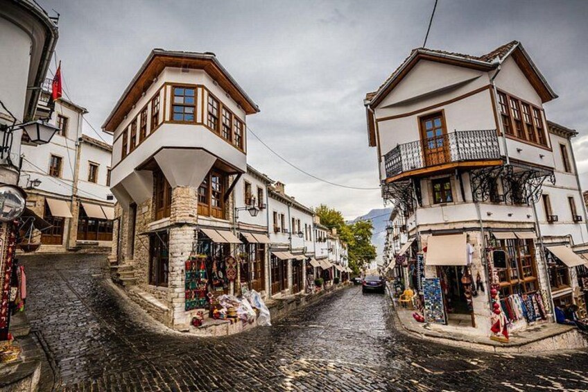 A cobblestone street lined with traditional buildings, a shop on the right, and a mountain in the background. 5