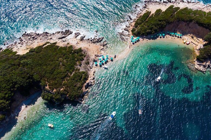 A coastal area with clear turquoise waters, a sandy beach, and a small island with greenery. 2