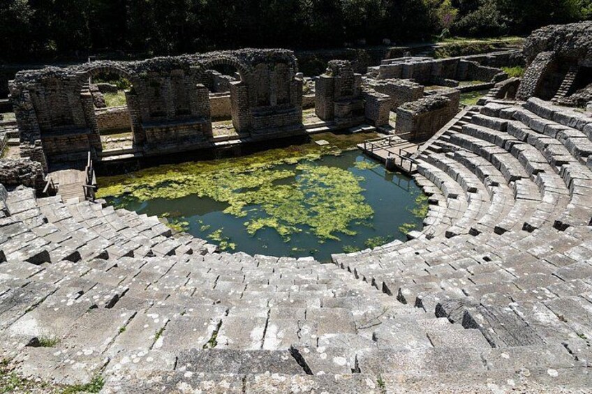 Ancient ruins with a circular amphitheater and a pond with algae. 3