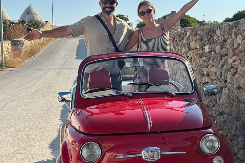 A red convertible car on a road with stone walls and a clear sky. 5