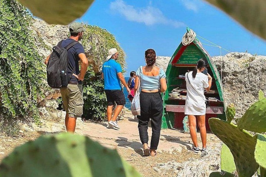 A group of people walking on a rocky path towards a green structure with a red roof. 3
