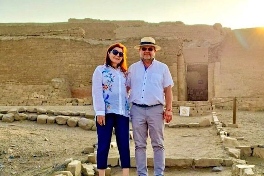 Two people standing in front of ancient ruins with stone steps and a doorway. 5