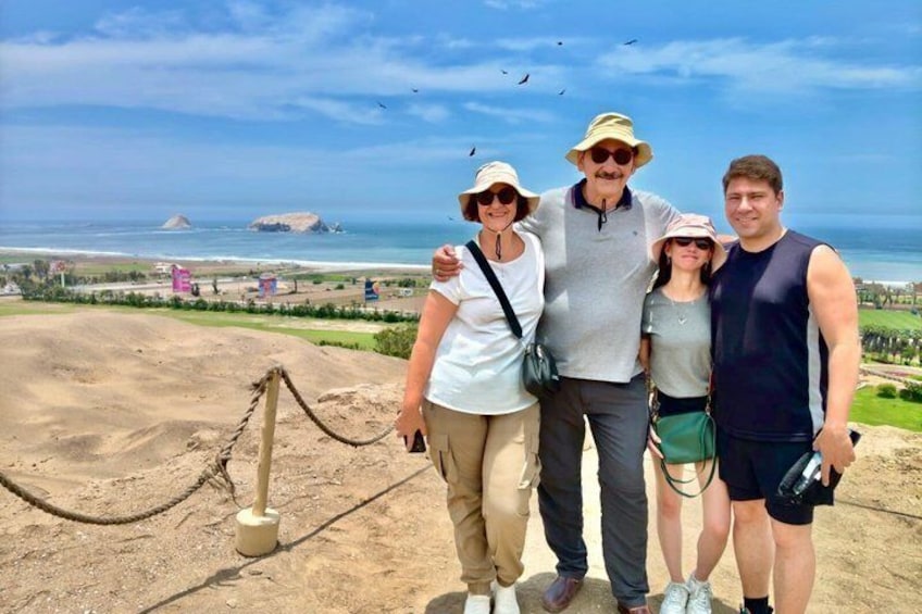 A group of people standing on a viewing platform with a coastal landscape in the background. 3
