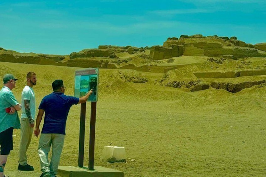 A group of people observing a large, ancient structure in a desert landscape. 2