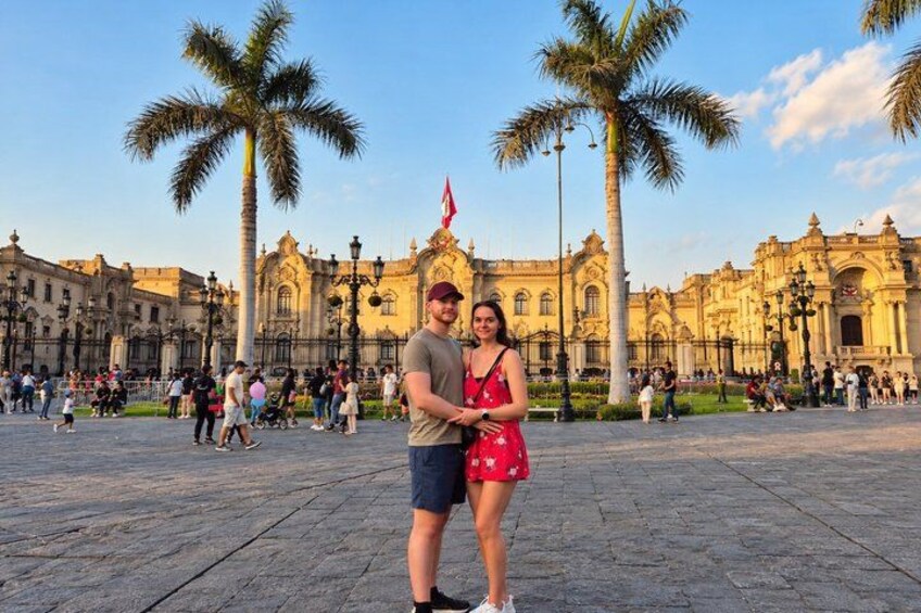 Una pareja parada en una plaza con un edificio histórico al fondo. 2