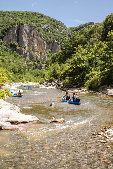 People rafting on a river surrounded by cliffs and greenery. 3