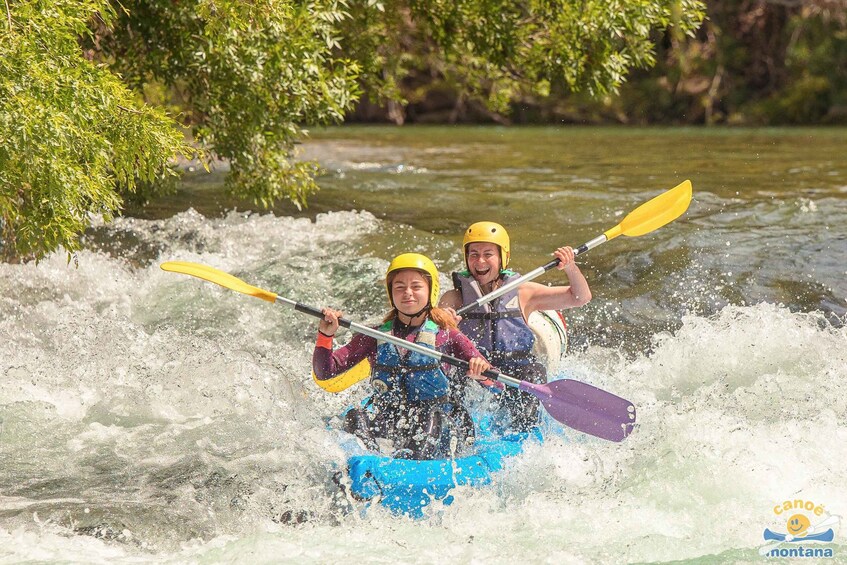Two people kayaking on a river surrounded by greenery. 2