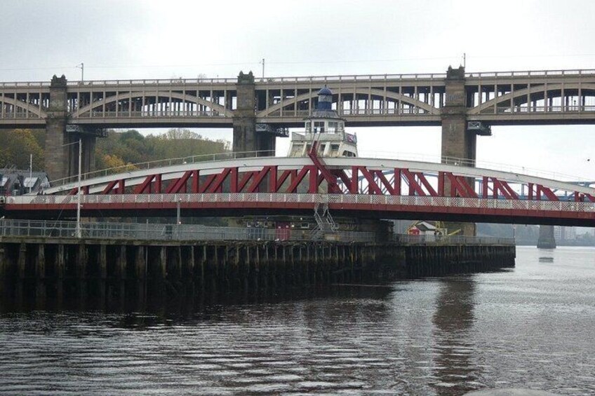 A bridge with a red truss structure spanning over a body of water. 2