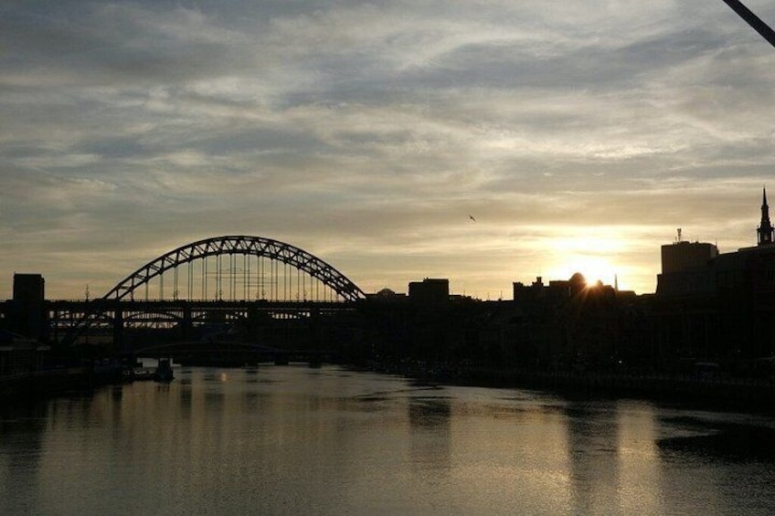 A bridge, a body of water, and a city skyline at sunset. 5