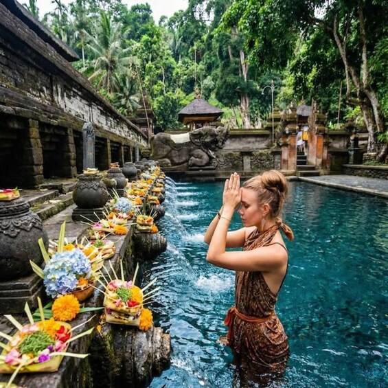 A person performing a ritual by a water feature with offerings. 4