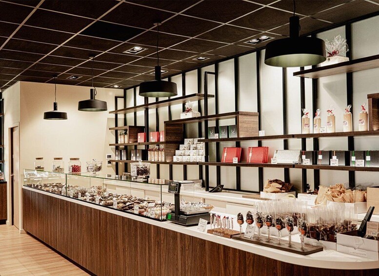A modern retail space with wooden shelves displaying various products, a central counter with food items, and pendant lighting. 2