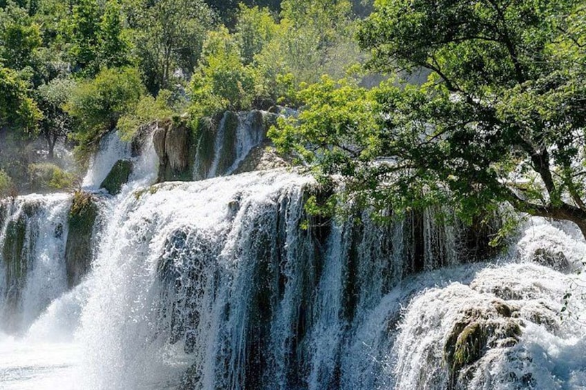Een waterval omringd door weelderige begroeiing. 1