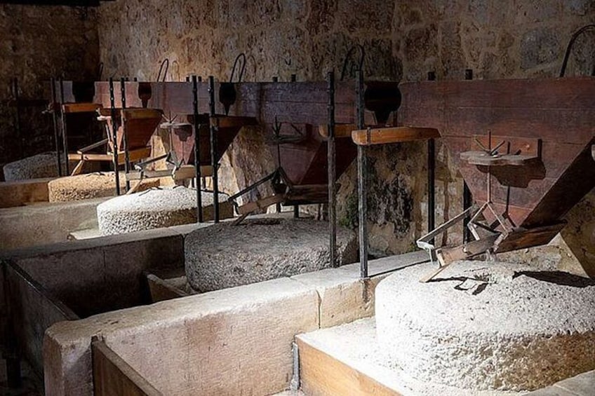 Een historische molen met stenen bakken en houten machines. 5