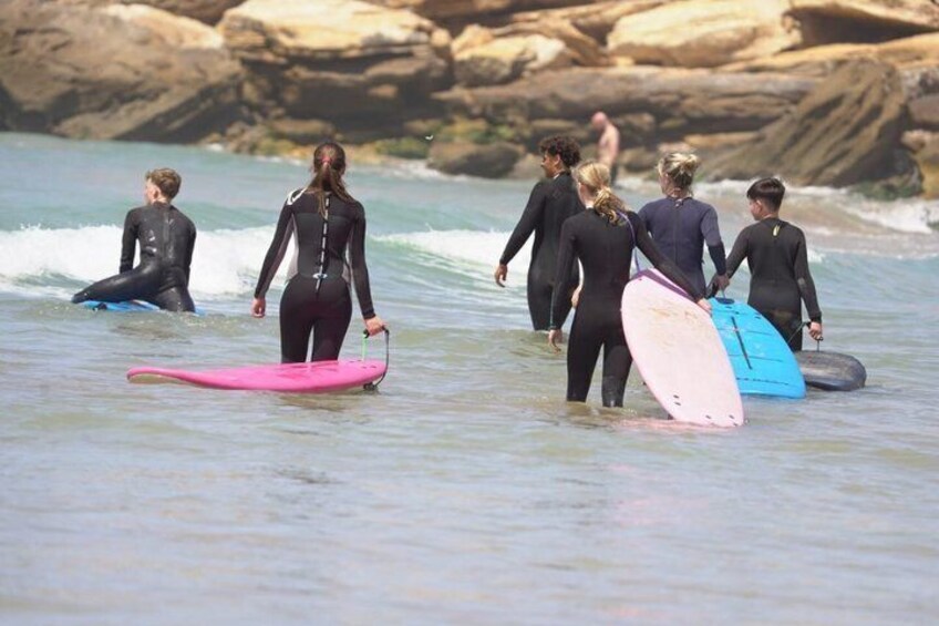 People in wetsuits walking into the ocean with surfboards. 5