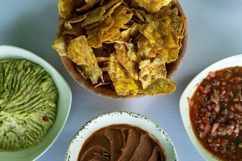 Eine Schüssel Tortilla-Chips, eine Schüssel Guacamole, eine Schüssel Salsa und eine Schüssel Schokoladensauce. 3