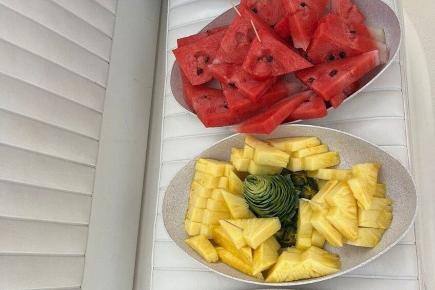 Zwei Teller mit Obstscheiben, einer mit Wassermelone und der andere mit Ananas, auf einer weißen Oberfläche. 2