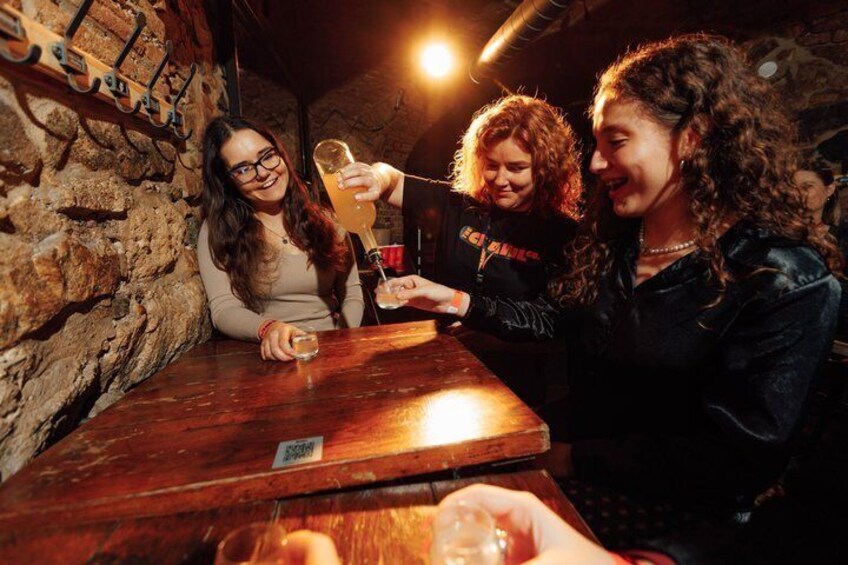 Three people at a bar with a wooden interior and stone wall. 3