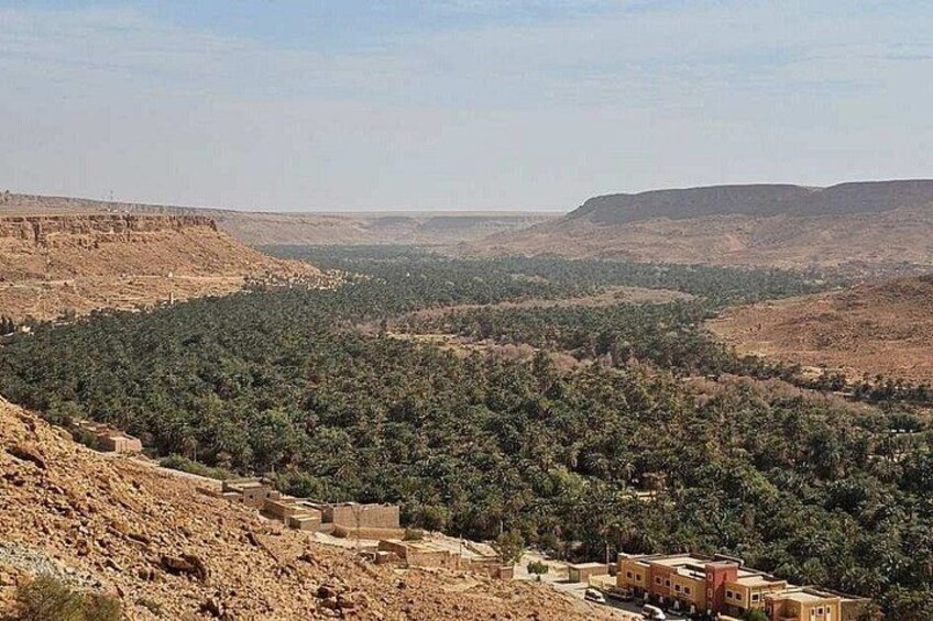 A rugged landscape with sparse vegetation, a few buildings, and distant hills. 4