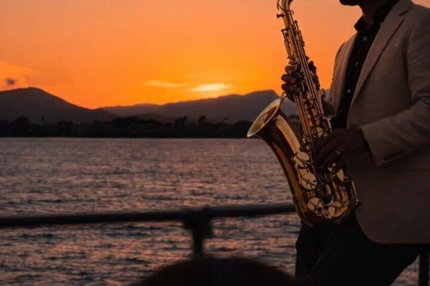 Una persona suona il sassofono in riva all'acqua al tramonto. 2