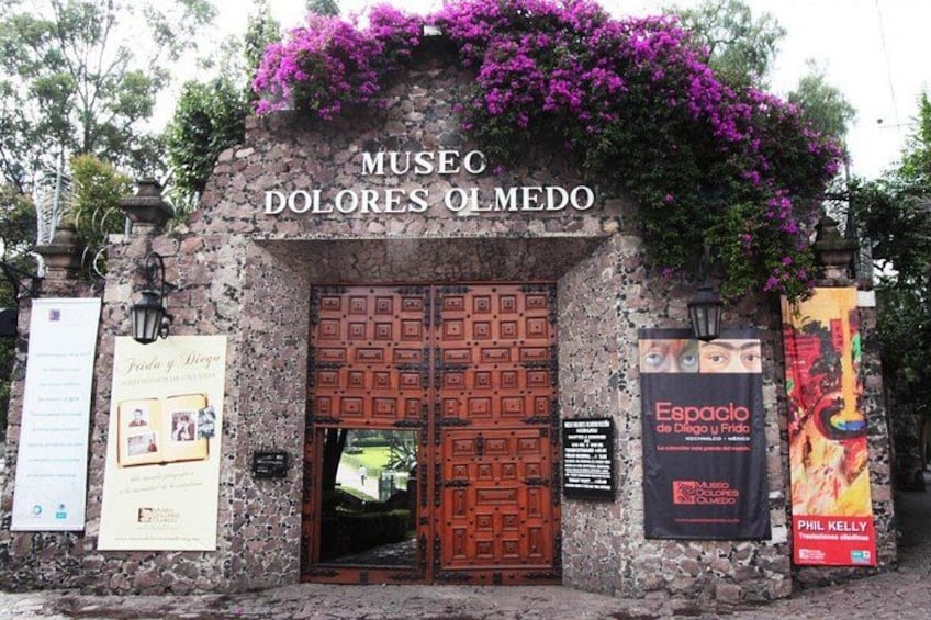 A museum entrance with a stone facade, wooden doors, and posters. 4