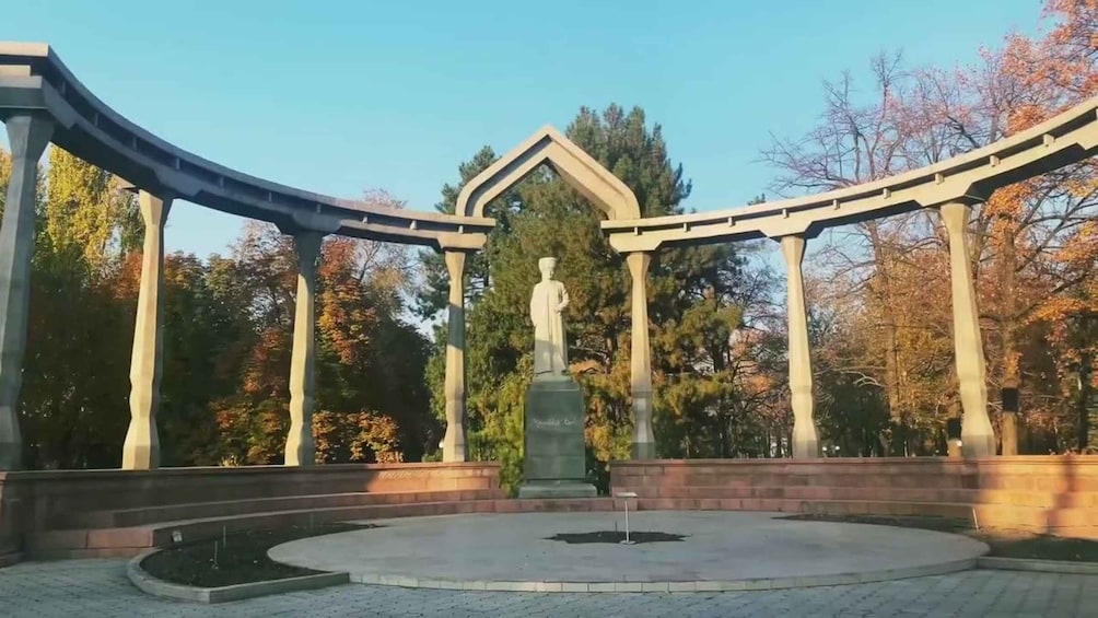 A circular monument with a statue in the center, surrounded by a curved structure with columns. 4